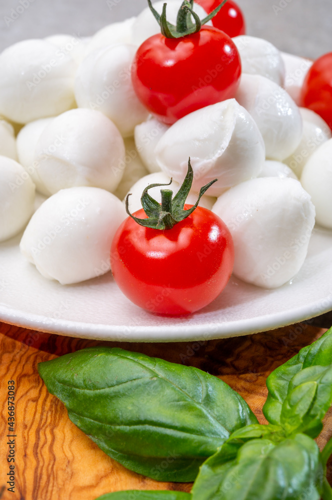 Italian tricolore, small balls of fresh white soft Italian mozzarella cheese, ripe red cherry tomatoes and fresh green basil herb, ready for making caprese salad