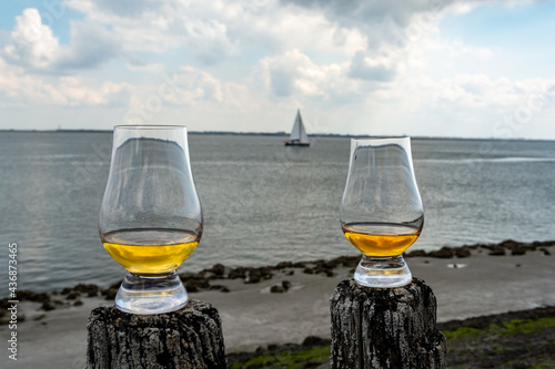 Photos Tasting of dram single malt scotch whisky on seashore in Scotland, old wooden po