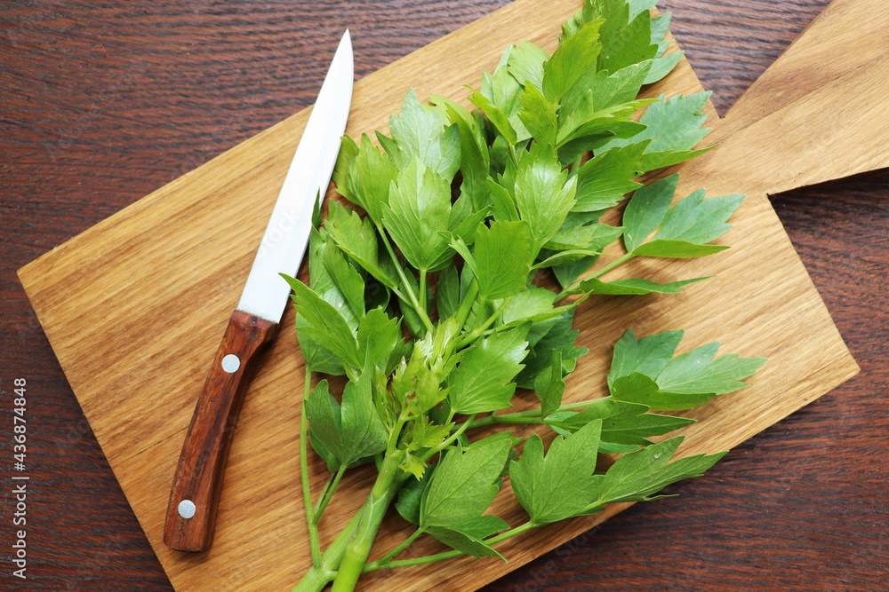Fresh green leaves of lovage or Levisticum officinale on a wooden cutting board Fresh green leaves of lovage or Levisticum officinale on a wooden cutting board