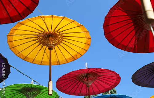 Under side of yellow handmade paper umbrella and others with blue sky background. 