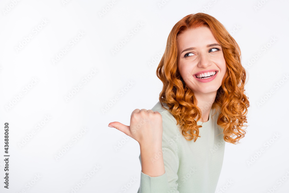 Photo portrait of red haired woman smiling curious showing thumb empty space recommending isolated white color background Photo portrait of red haired woman smiling curious showing thumb empty space recommending isolated white color background