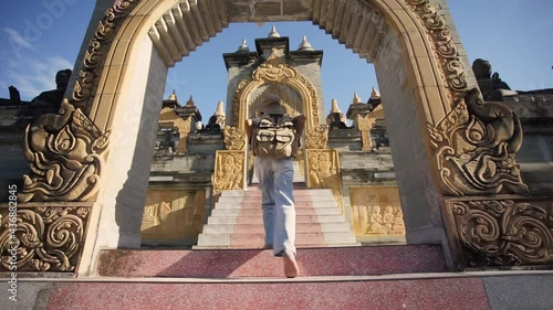 Behind female traveler wearing a hat with backpack travel walking in the attraction architecture pagoda of buddhist culture in southeast Asia. Pagoda of Buddhist in Thailand. photo