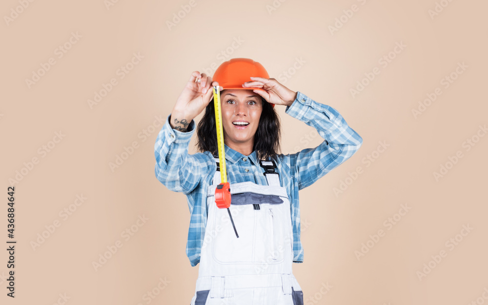 cheerful lady repairman in uniform on blue background, measurement
