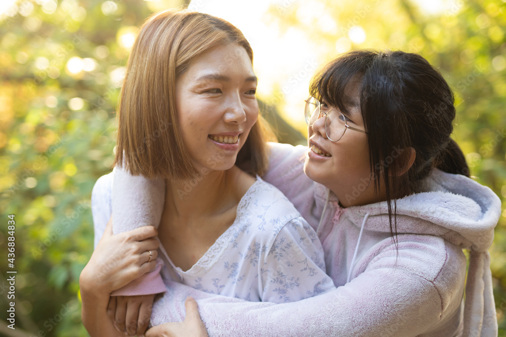 Portrait of smiling asian woman with her daughter embracing in garden Portrait of smiling asian woman with her daughter embracing in garden
