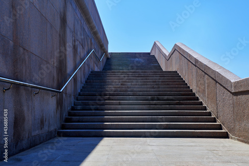 Wide stone staircase. Way up to blue sky in sunny day. Concept of hope and bright future. Freedom, career or success concept. Granite stairs.