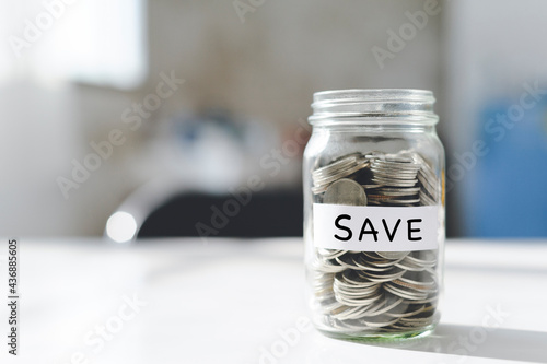 Coins in glass money jar on the table with the save label, financial concept. Saving concept.