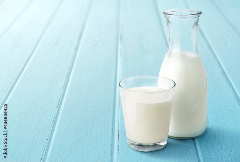 A glass and bottle of fresh milk on light blue wood board. A glass and bottle of fresh milk on light blue wood board.