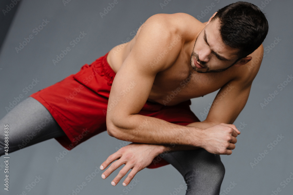 Young shirtless sportsman doing exercise while working out indoors