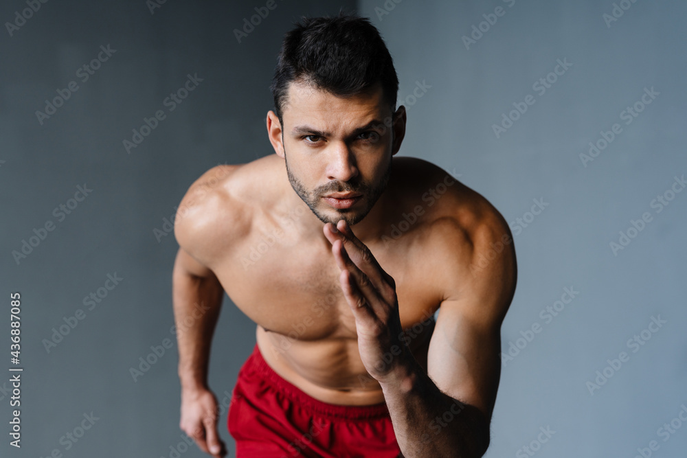 Young shirtless sportsman doing exercise while working out indoors Young shirtless sportsman doing exercise while working out indoors