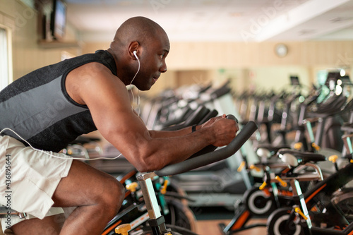 Athletic black man doing cardio workout on exercise bike in gym. Concept of sport and healthy lifestyle.