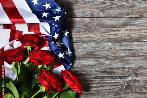Fototapeta Naklejka Na Ścianę i Meble -  Independence Day USA concept. Memorial Day. Red roses with USA flag on a wooden background. Top view, flat lay with copy space.