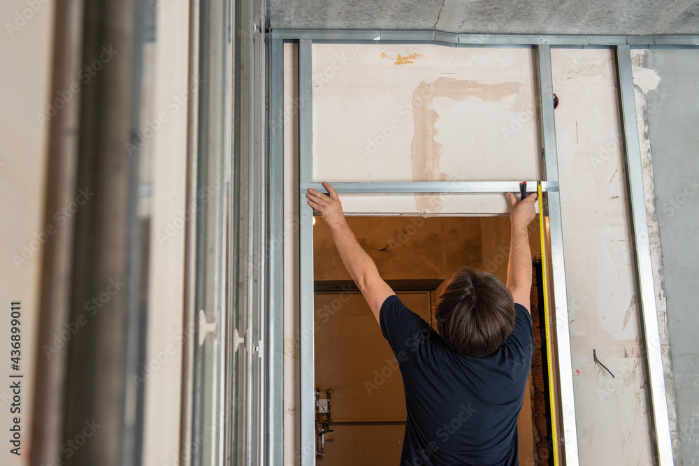 Male worker attaches profile for drywall for room soundproofing. Construction work, repair. Renovation Male worker attaches profile for drywall for room soundproofing. Construction work, repair. Renovation