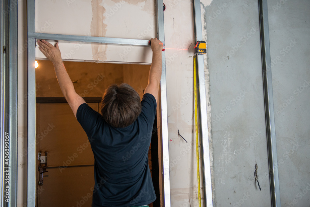 Male worker attaches profile for drywall for room soundproofing. Construction work, repair. Renovation Male worker attaches profile for drywall for room soundproofing. Construction work, repair. Renovation