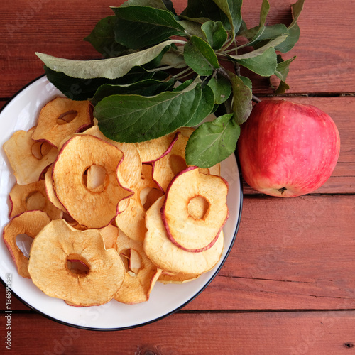 Homemade sun-dried organic apple slices, crispy apple chips, on an old rustic wooden table with fresh apple. Healthy snack. The concept is a healthy diet. Chips are part of a vegetarian diet.
