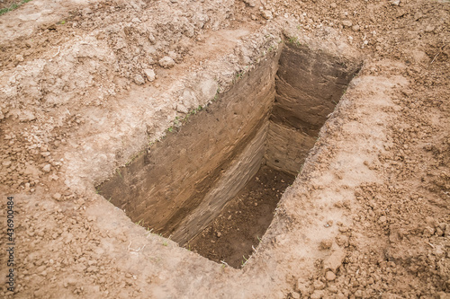A pit dug in the ground. A grave. Fototapet
