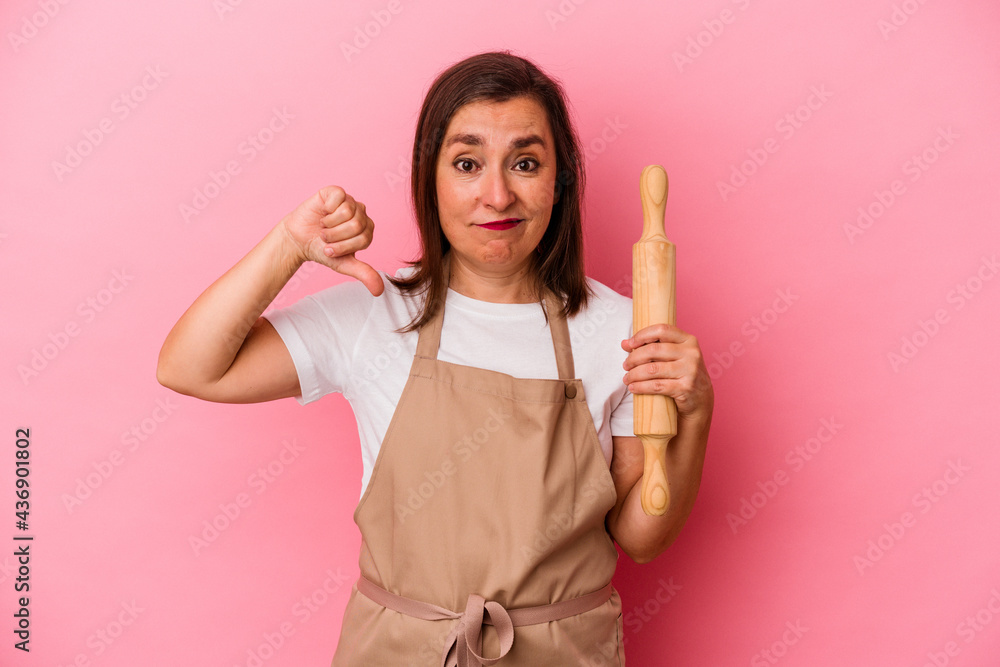 Middle age pastry chef woman isolated on pink background showing a dislike gesture, thumbs down. Disagreement concept. Middle age pastry chef woman isolated on pink background showing a dislike gesture, thumbs down. Disagreement concept.