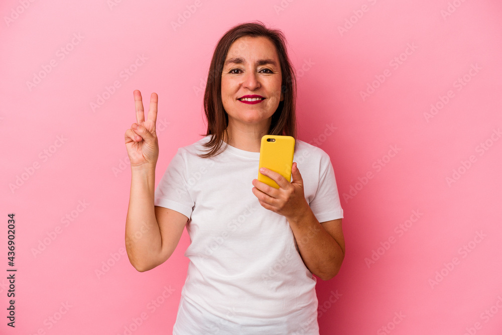 Middle age caucasian woman holding mobile phone isolated on pink background showing number two with fingers. Middle age caucasian woman holding mobile phone isolated on pink background showing number two with fingers.