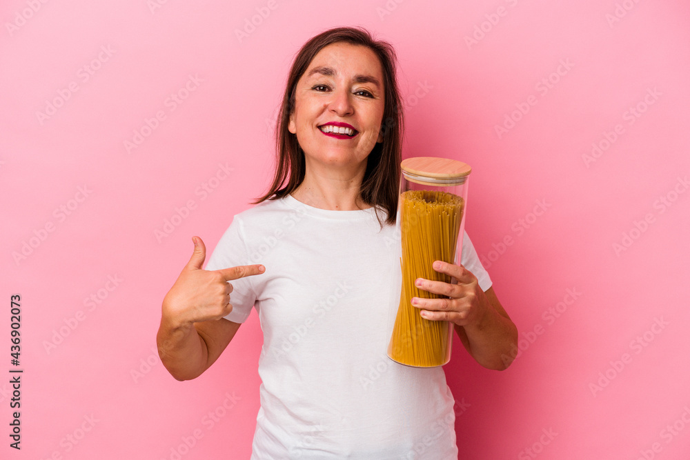 Middle age caucasian woman holding a pasta jar isolated on pink background person pointing by hand to a shirt copy space, proud and confident Middle age caucasian woman holding a pasta jar isolated on pink background person pointing by hand to a shirt copy space, proud and confident