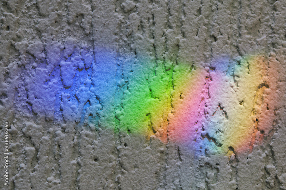 Detail of textured wall with solar bunnies, plashes of sunlight. Decomposition of light into a color spectrum.