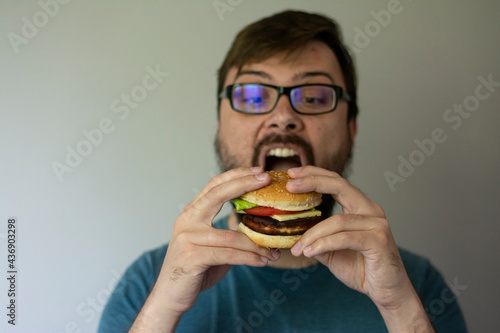  Handsome young brunette man eating hamburger fast food