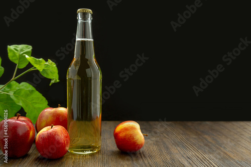 Red apples and cider in a glass bottle