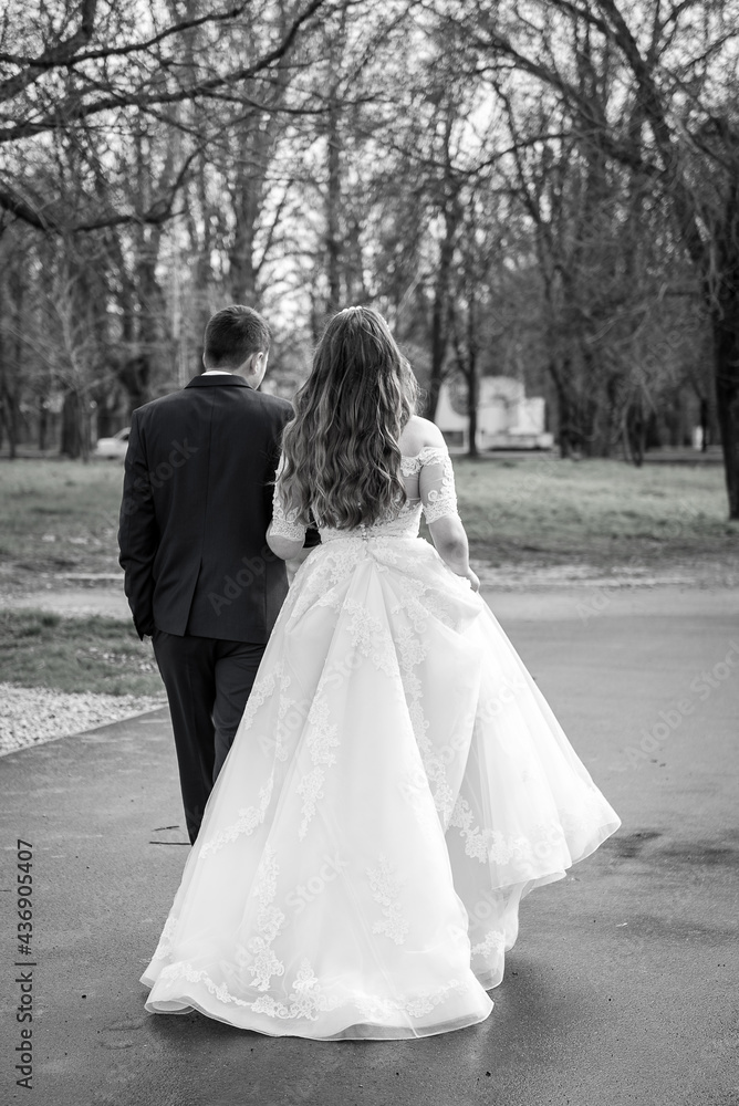The bride and groom stand back, hold hands