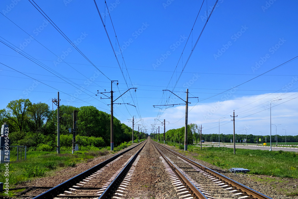 Railway railroad tracks rails wires poles at large city station a bright summer day