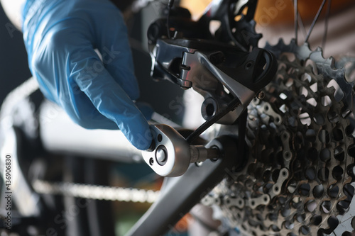 Gloved handyman repairs rear cassette of sports bike