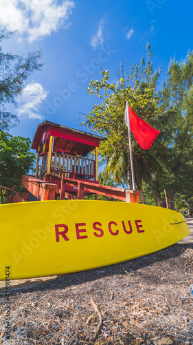 Red Lifeguard tower and yellow rescue board with red warning flag © RandomHartz
