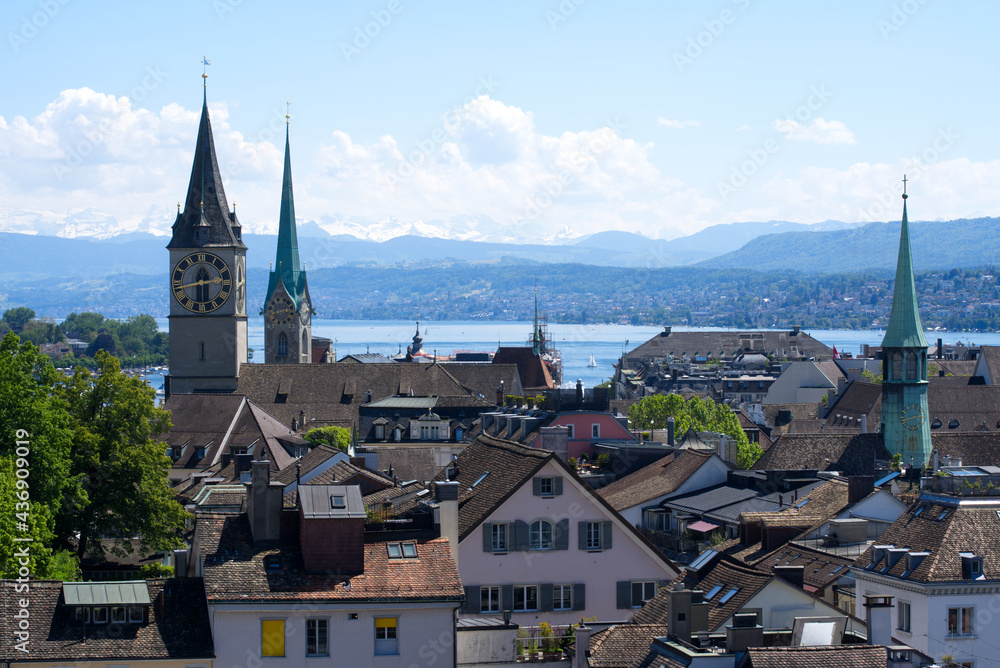 Old town of Zurich with churches Sankt Peter (Saint Peter) and Fraumünster (Women's Minster) with lake Zurich and Swiss alps in the background. Photo taken June 1st, 2021, Zurich, Switzerland.