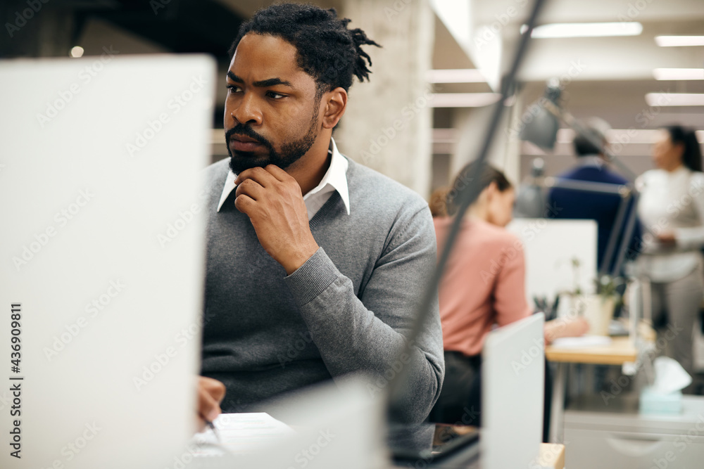 Fototapeta premium African American entrepreneur taking notes while working on a computer in the office.