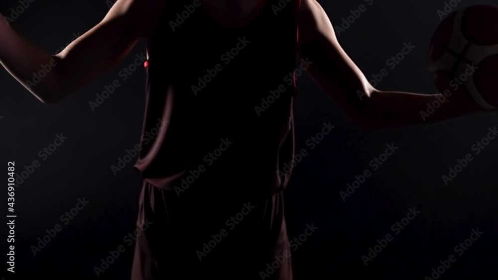 Young basketball player in a dark studio on a black background. Close up of an athlete's wet hands, holding a basketball, hits the ball with one hand, forming an explosion of splashes. Slow motion. Young basketball player in a dark studio on a black background. Close up of an athlete's wet hands, holding a basketball, hits the ball with one hand, forming an explosion of splashes. Slow motion.
