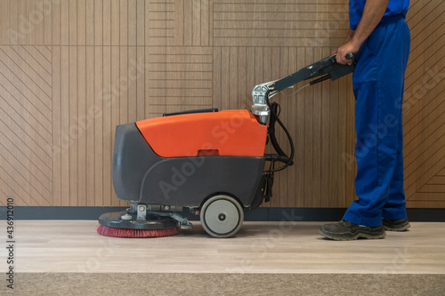 Cleaner cleans the floor with walk behind scrubber dryer machine
