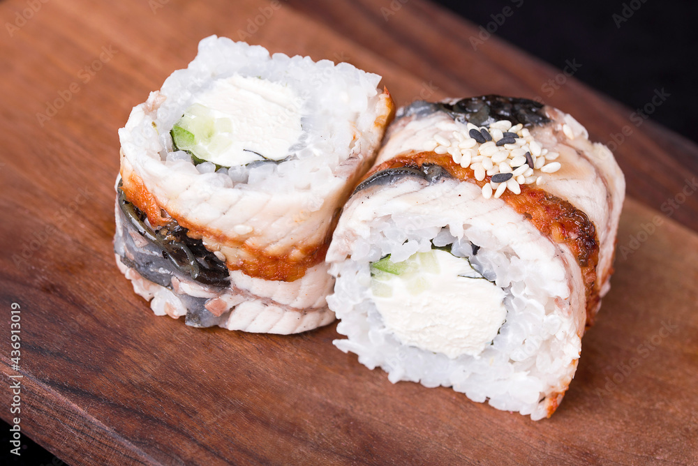 Delicious fresh rolls with red fish, awakad, cream cheese, lettuce, sesame seeds, on a wooden worthy.