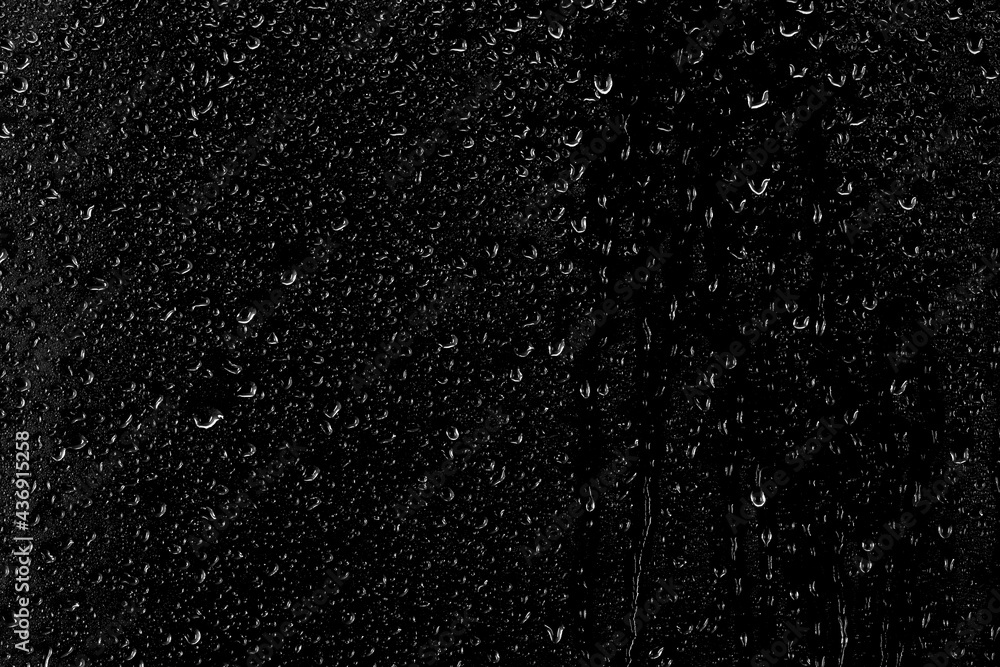 Drops of water flow down the surface of the clear glass on a black background. Texture for creativity.	
