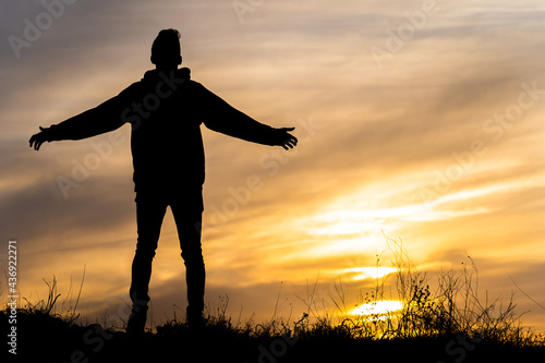 chico joven de espaldas a contra luz atardecer