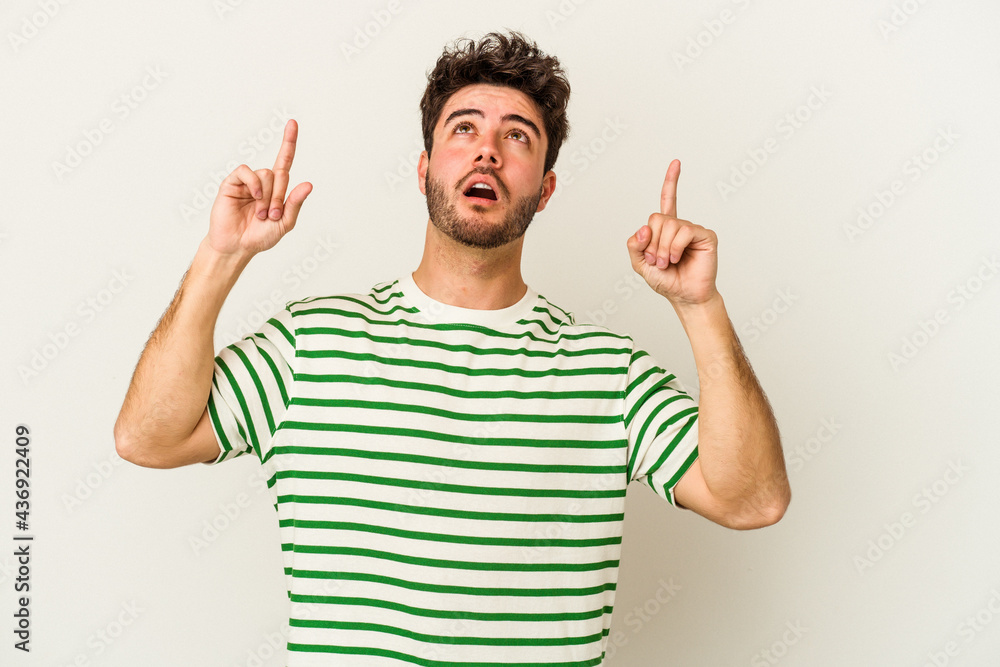 Young caucasian man isolated on white background pointing upside with opened mouth. Young caucasian man isolated on white background pointing upside with opened mouth.