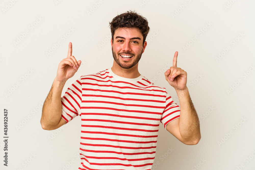 Young caucasian man isolated on white background indicates with both fore fingers up showing a blank space. Young caucasian man isolated on white background indicates with both fore fingers up showing a blank space.
