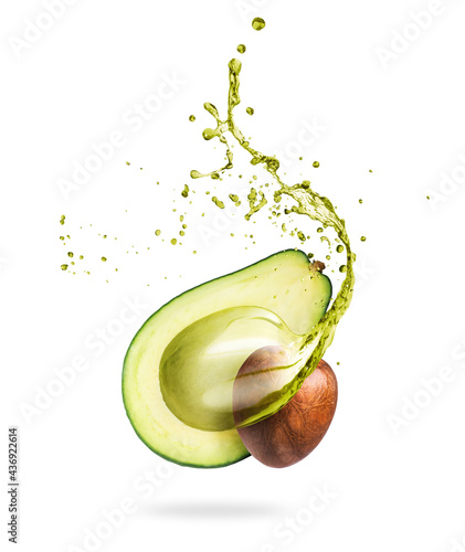 Leinwand Poster Half of sliced avocado with splashes of juice close-up, isolated on a white back