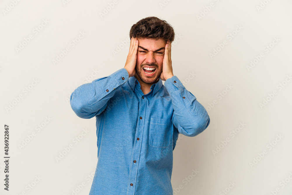 Young caucasian man isolated on white background covering ears with hands trying not to hear too loud sound. Young caucasian man isolated on white background covering ears with hands trying not to hear too loud sound.