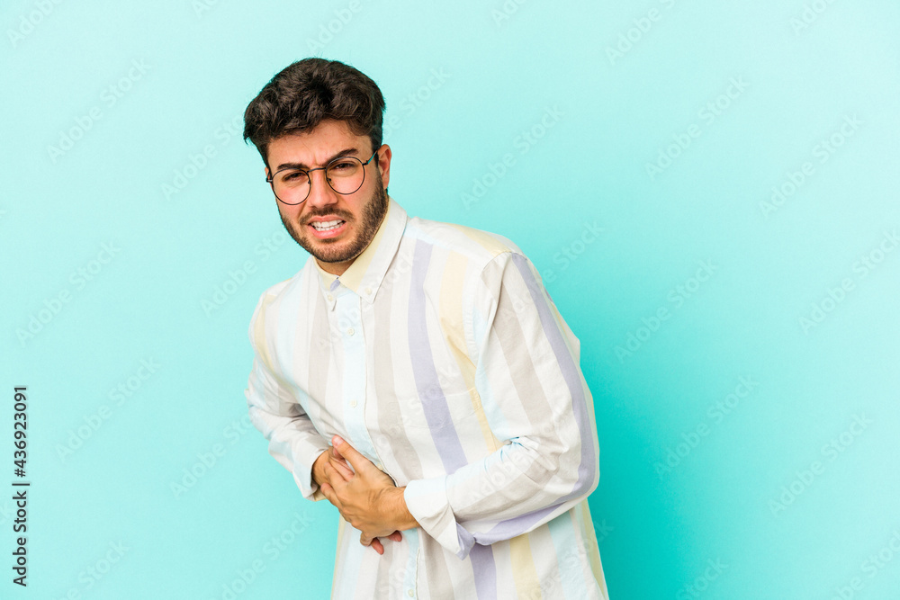 Young caucasian man isolated on blue background having a liver pain, stomach ache. Young caucasian man isolated on blue background having a liver pain, stomach ache.