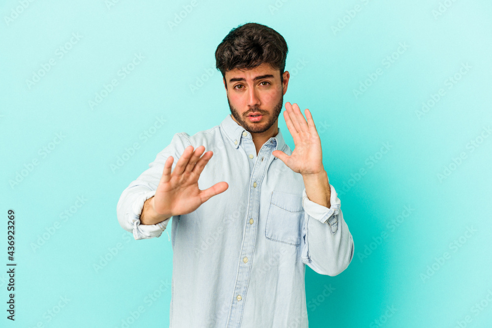 Young caucasian man isolated on blue background rejecting someone showing a gesture of disgust. Young caucasian man isolated on blue background rejecting someone showing a gesture of disgust.