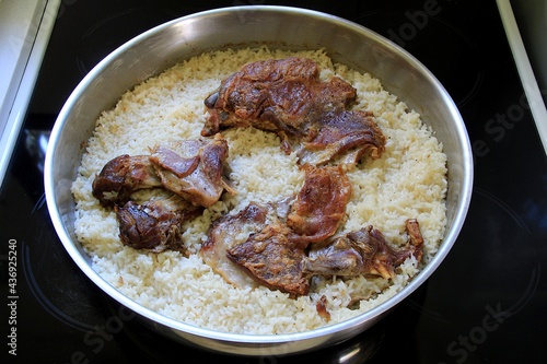 Baked rice and lamb meat in the oven in a baking pan. Top view, selective focus