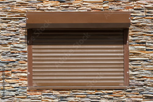 decorative stone wall and window with roller shutters for background or texture