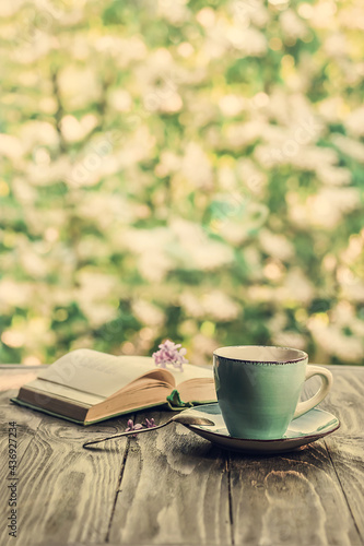 Morning coffee. Cup of coffee and an open book on a wooden table in the garden. Life style.