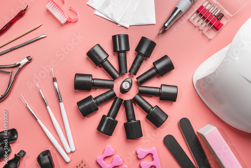 manicure and pedicure tools and other nail essentials on pink background top view. nail work flat lay concept