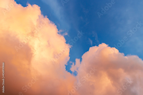 Beautiful cloudscape - pink-orange clouds in the rays of the sun against the blue sky