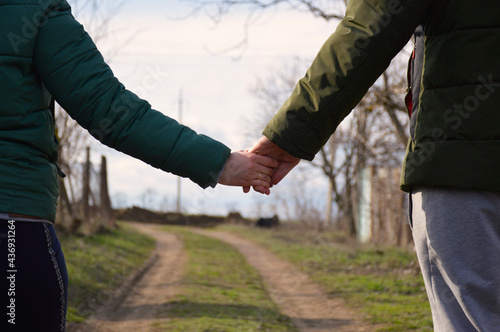 a married couple holds hand at sunset, against the background of a dirt country road
