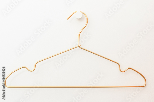 a wire hanger hangs on a hook against a white wall