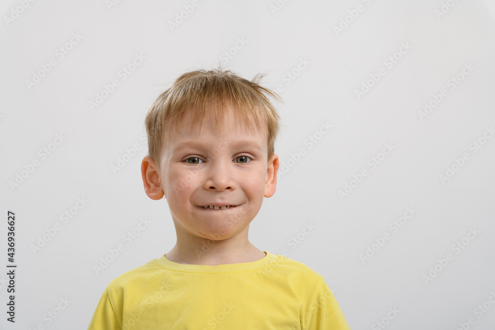 portrait of a little boy in a yellow t-shirt on a white background. On the face of a smile portrait of a little boy in a yellow t-shirt on a white background. On the face of a smile